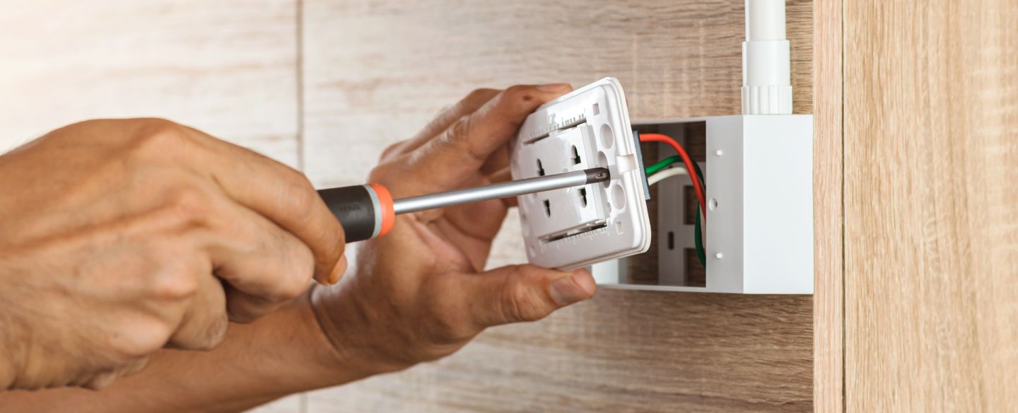 electrician using a screwdriver to install a power outlet denver nc